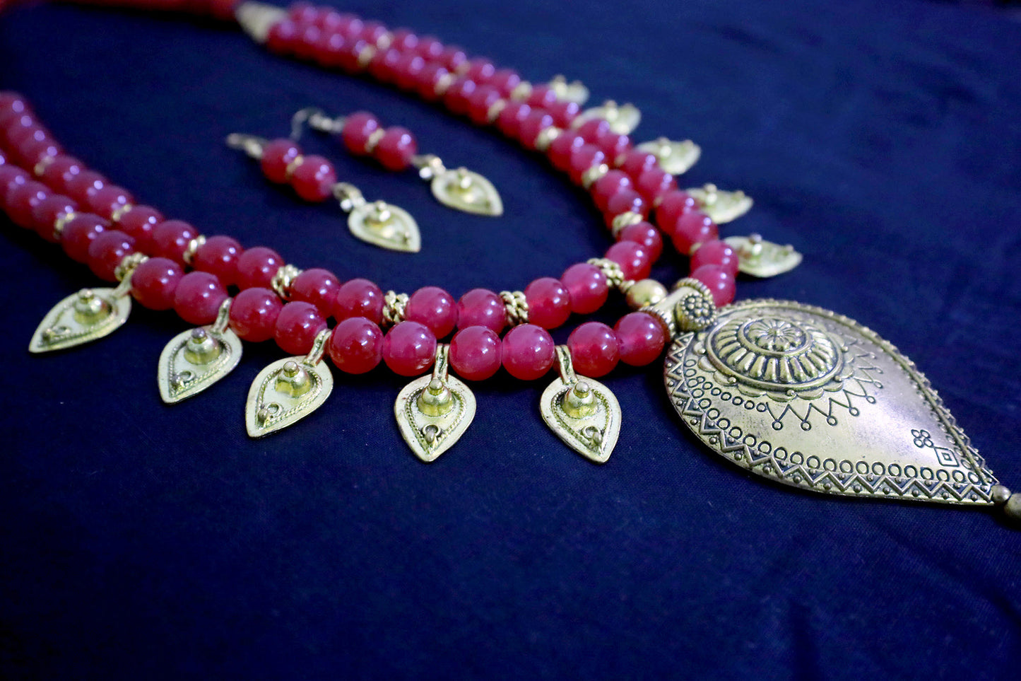 Angle view of red handmade glass beads golden drop pendant necklace with earrings set.