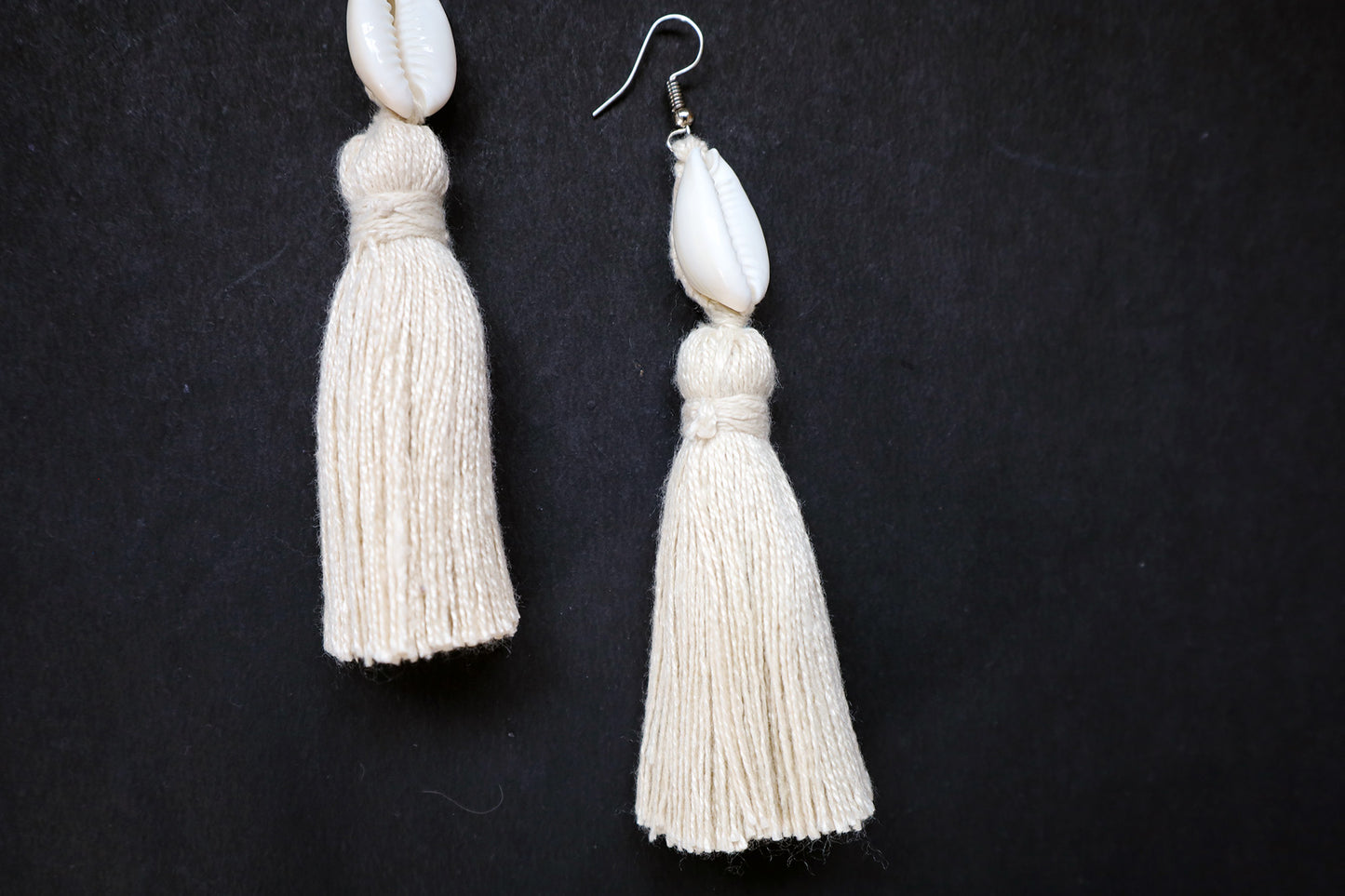 Close-up of a single Cowrie Seashell & Off-white Tussle Dangle Earring highlighting detailing and texture