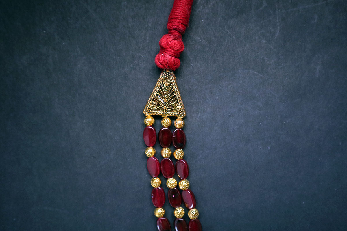 Close-up of left side of 3 layered golden balls & oval glass beaded necklace on a dark background – fashion jewellery online