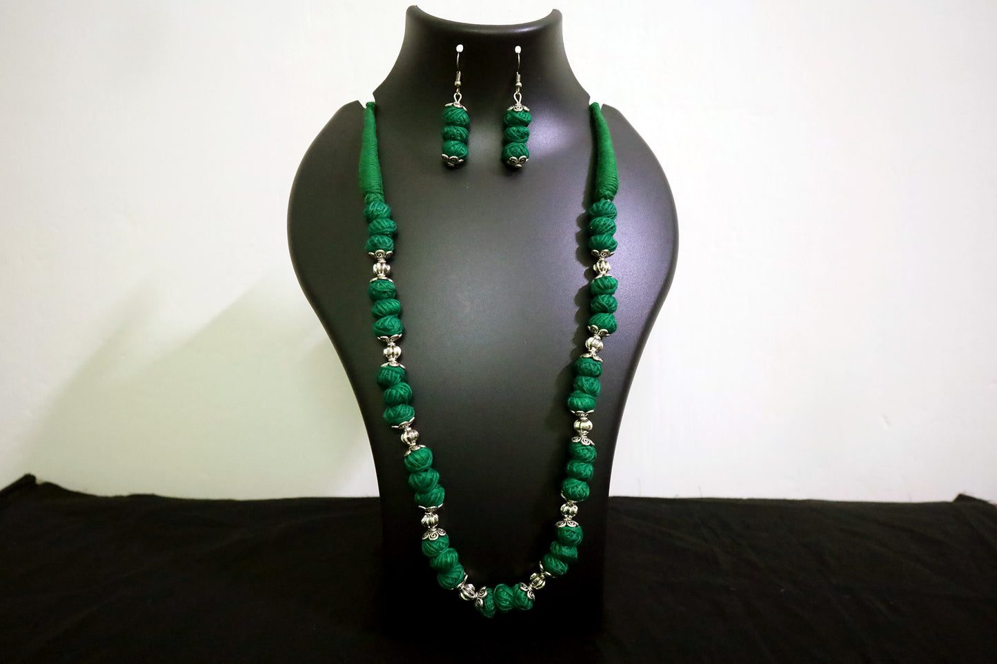 Closer view of green oxidized cotton balls long necklace with earrings on mannequin.