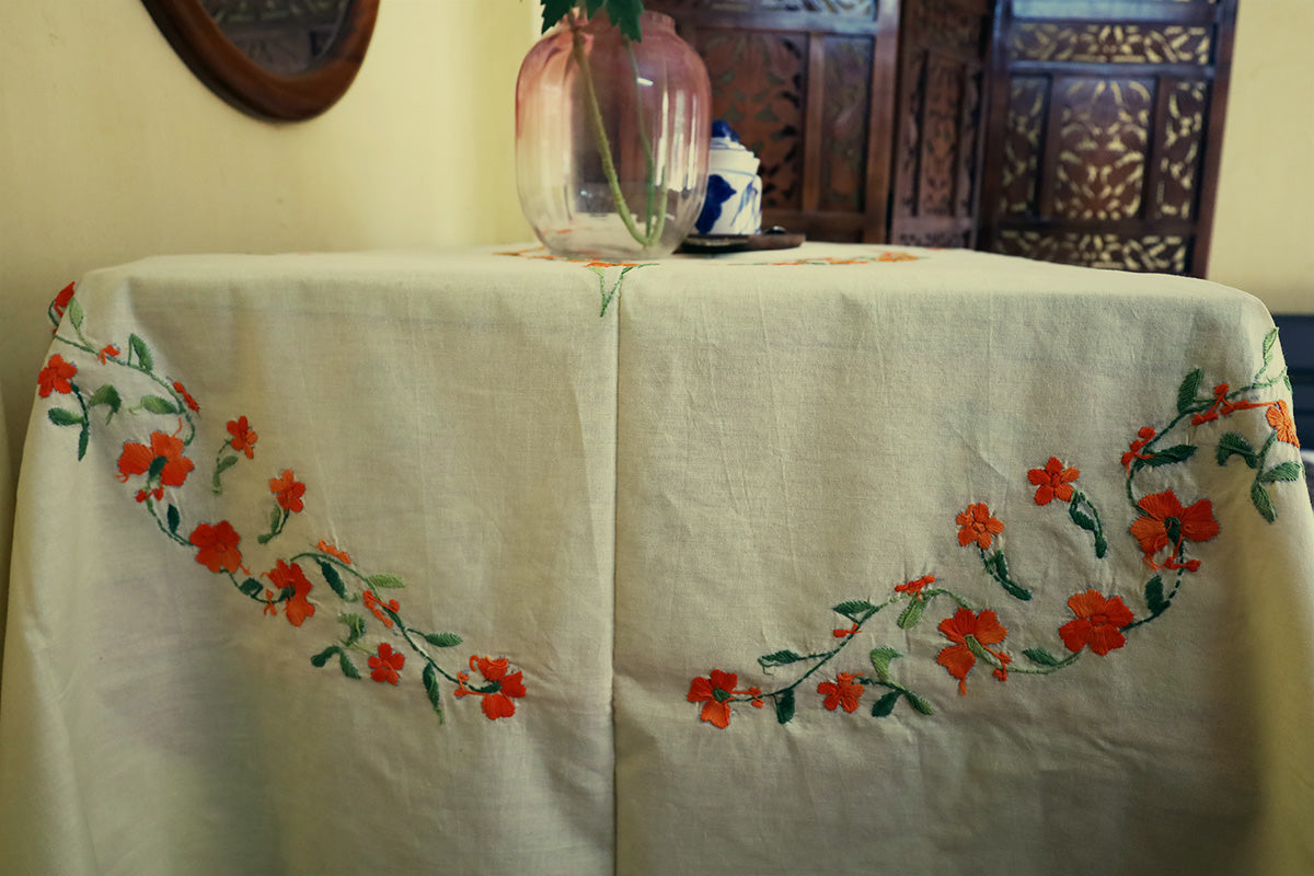 Close-up of Bright Orange Hand Embroidery Table Cloth’s embroidery patterns next to a chest of drawers.