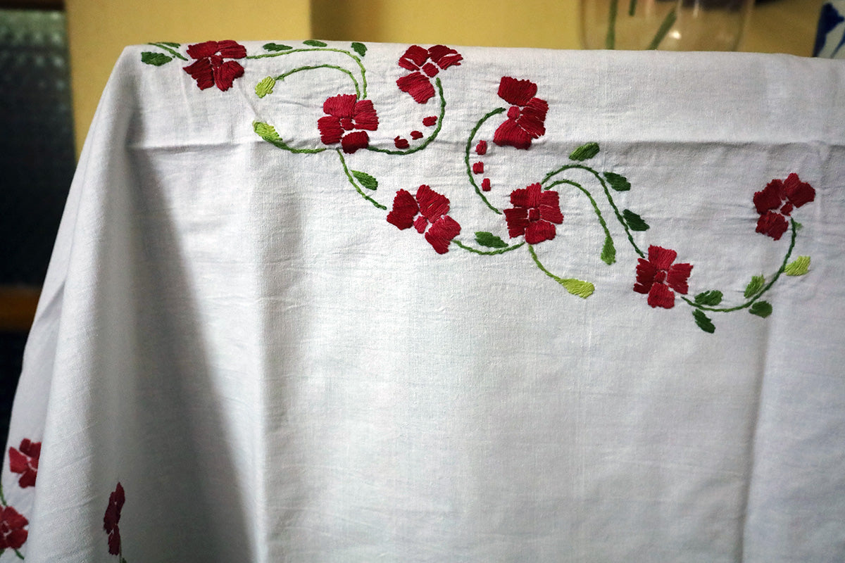 Close-up of Crimson Red Hand Embroidery Table Cloth’s detailed patterns beside a chest of drawers.