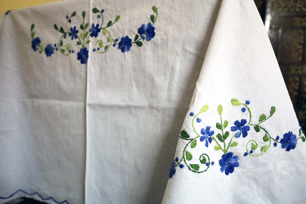 Close-up of Navy Blue Hand Embroidery Table Cloth’s intricate embroidery beside a chest of drawers.