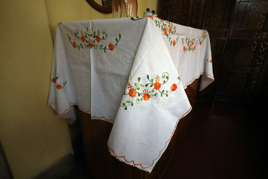 Side angle view of Orange Hand Embroidery Table Cloth with a chest of drawers, highlighting its vibrant embroidery.