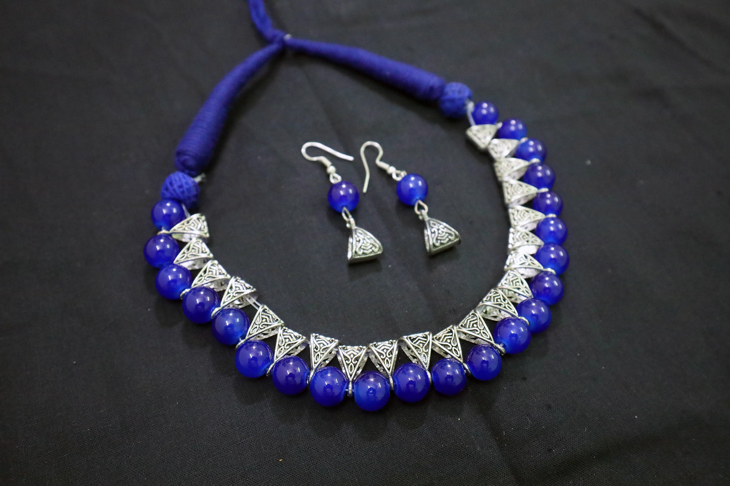 Angle view of navy blue glass beads silver loop necklace with earrings