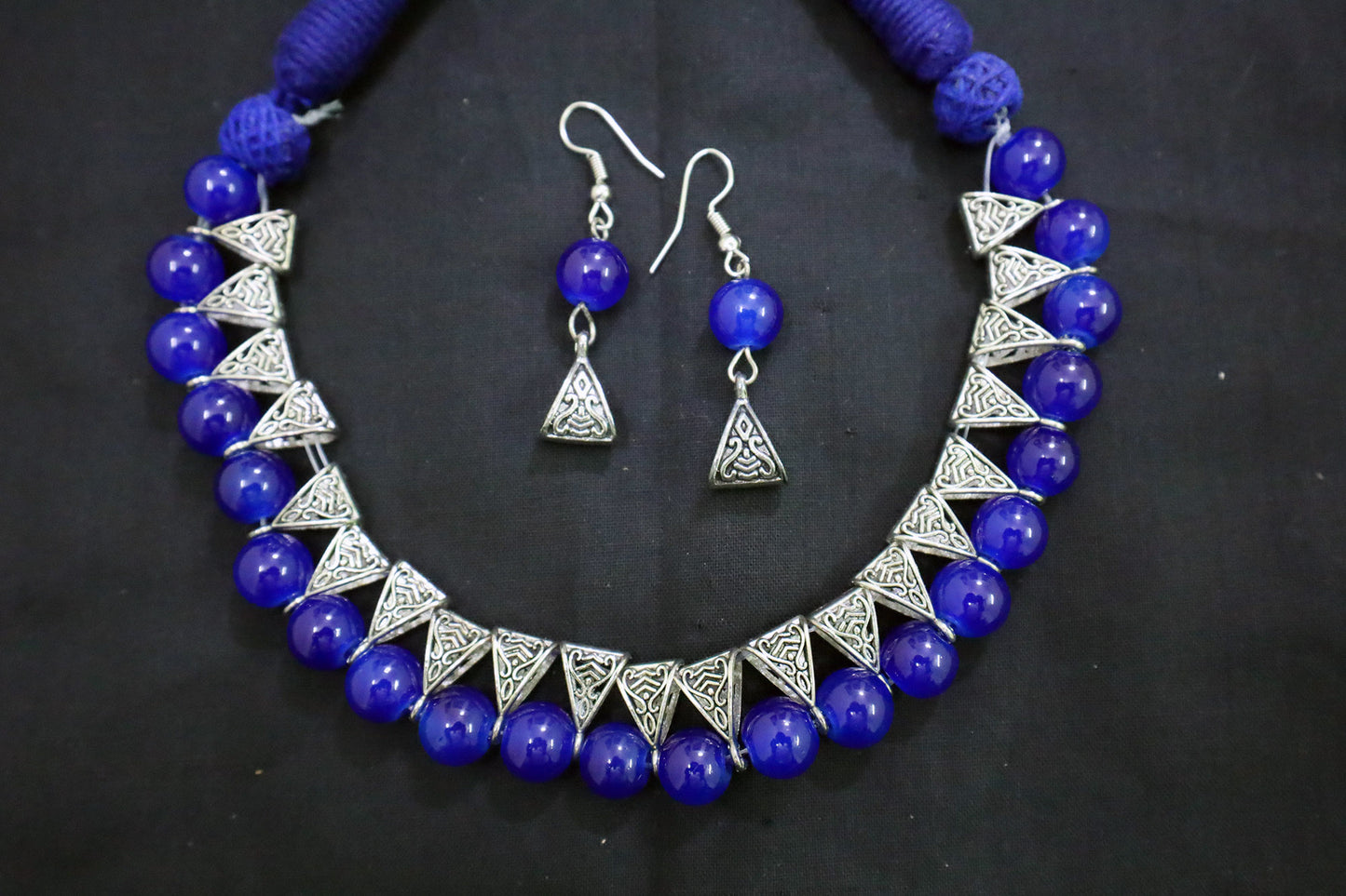 Bottom close-up of navy blue glass beads silver loop necklace and earrings