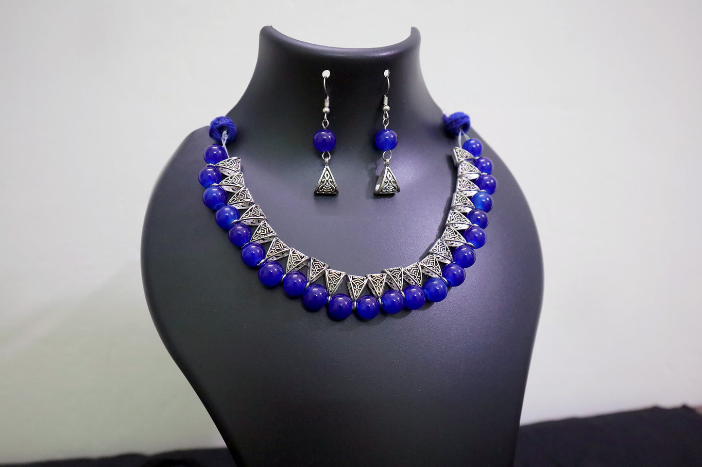 Closer view of navy blue glass beads silver loop necklace set on black mannequin