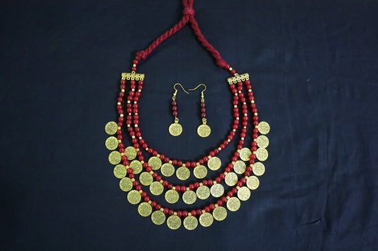 Top view of 3 layered glass beads and golden ginni necklace set with earrings on black background