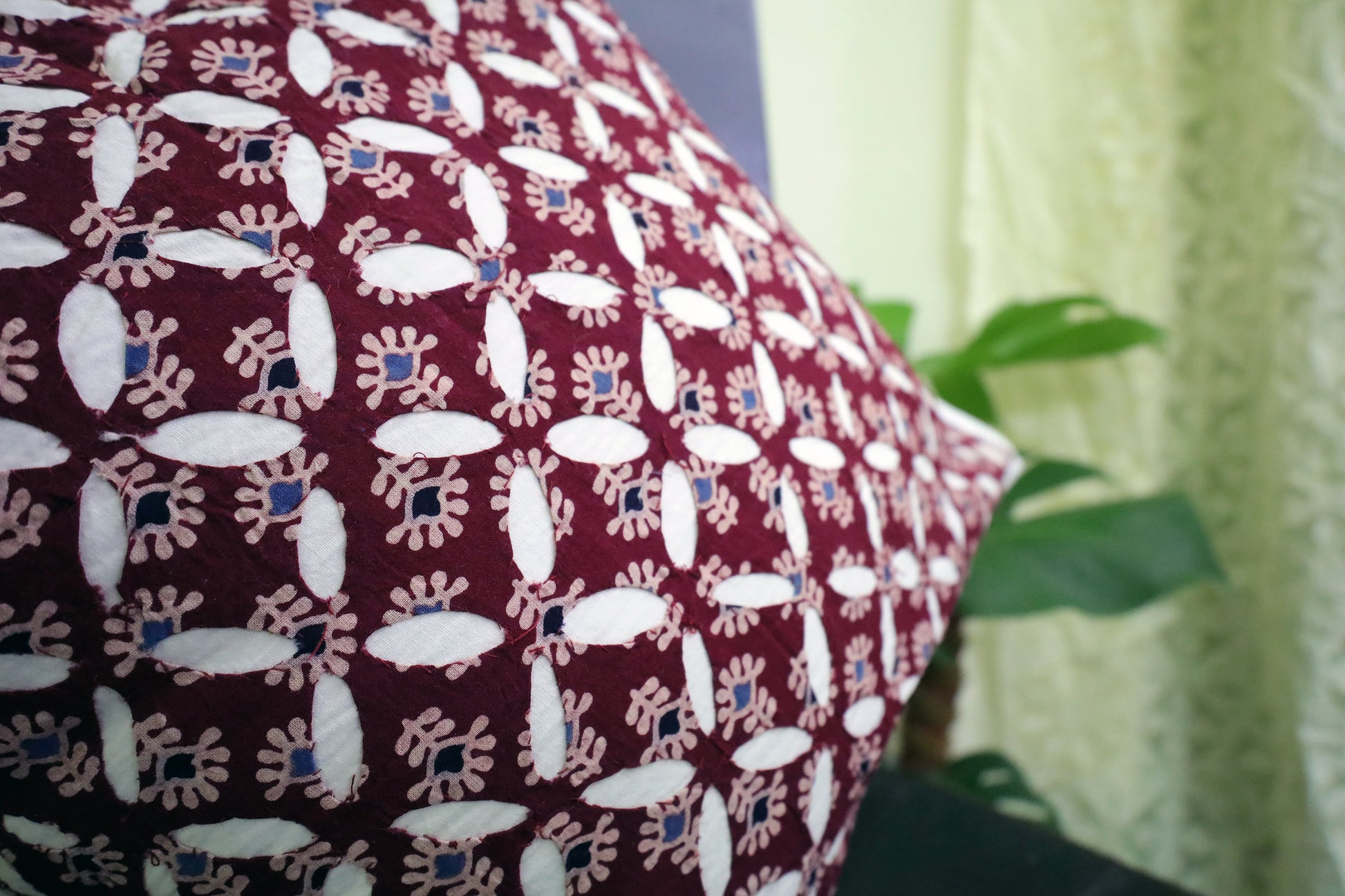 A beautiful display of a Maroon Cutwork Ajrakh Print Cushion Cover