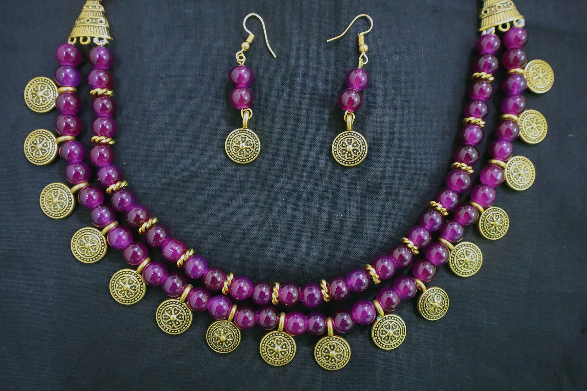 Bottom close-up of amethyst 2 layered glass beads golden ginni necklace and earrings