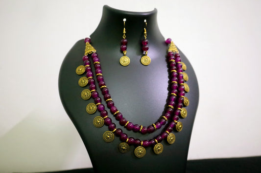 Closer view of amethyst 2 layered glass beads and golden ginni necklace with earrings on black mannequin