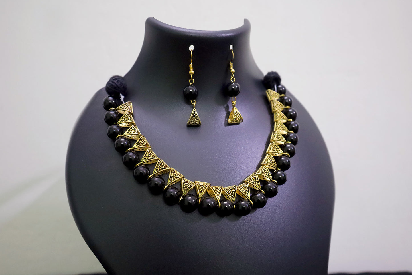 Closer view of black glass beads golden loop necklace set on black mannequin