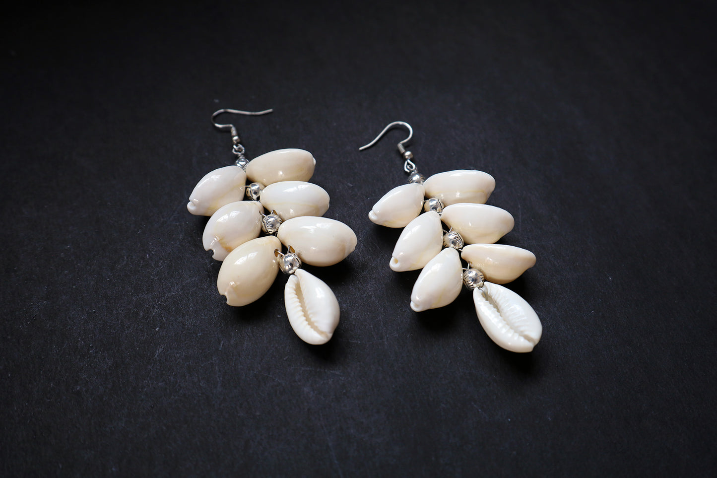 Angled view of pair of Cowrie Seashell & Metal Ball Dangle Earrings highlighting oxidised detailing