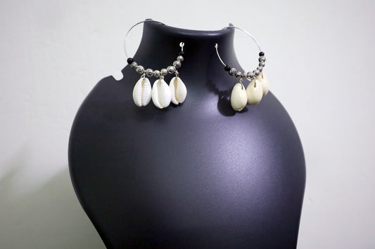 Close-up view of pair of Cowrie Seashell & Metal Ball Medium Hoop Earrings on black mannequin