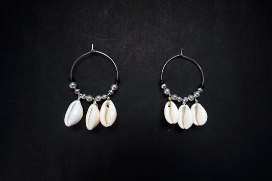 Top view of handcrafted pair of Cowrie Seashell & Metal Ball Hoop Earrings on black fabric background