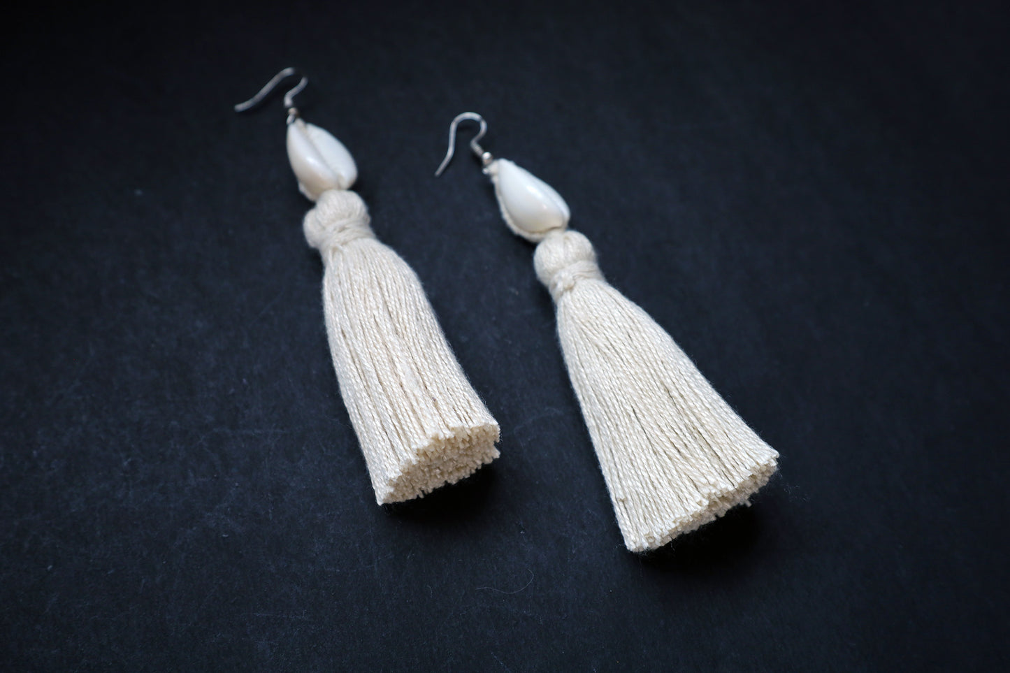 Angled view of Cowrie Seashell & Off-white Tussle Dangle Earrings showcasing boho style design