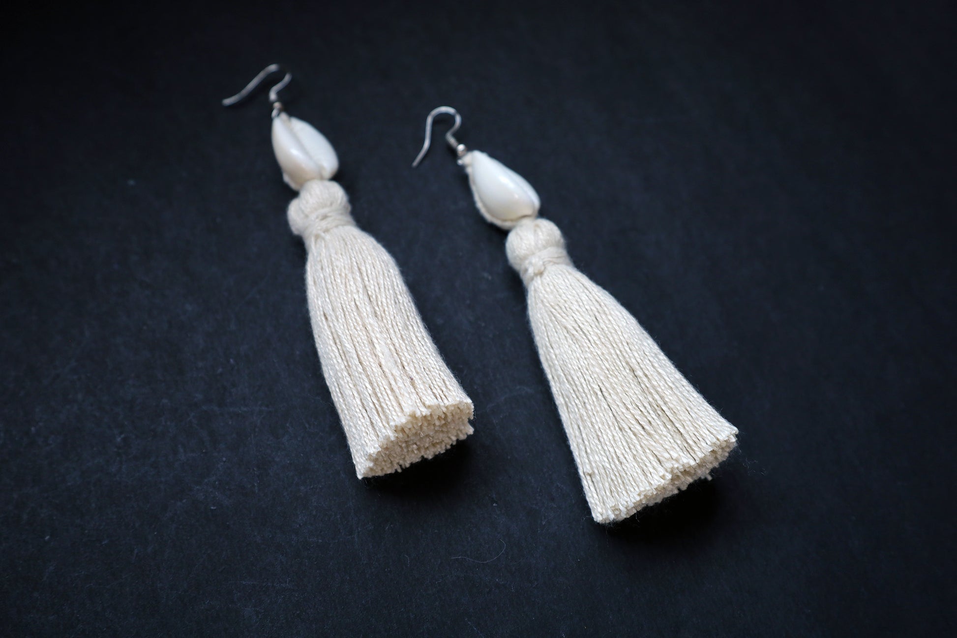 Angled view of Cowrie Seashell & Off-white Tussle Dangle Earrings showcasing boho style design