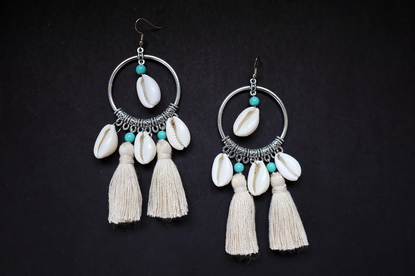 Top view of handcrafted pair of cowrie seashell and tussle oxidized hoop dangle earrings