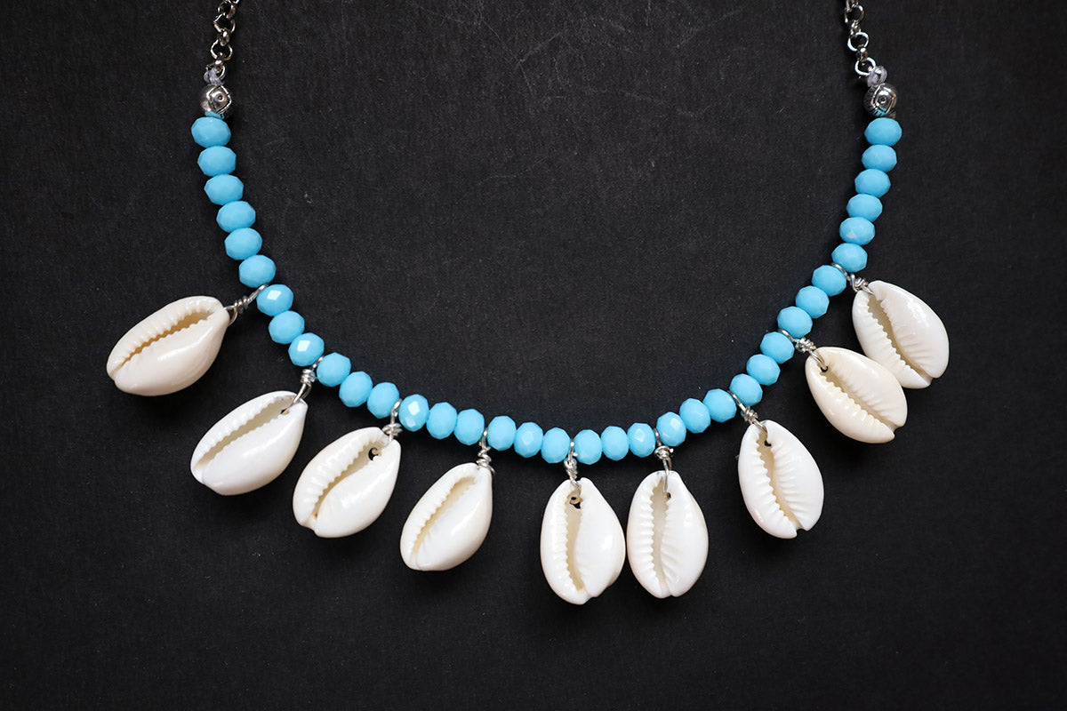 Bottom close-up of turquoise crystal beads & cowrie short necklace on a dark background – artificial jewellery for women