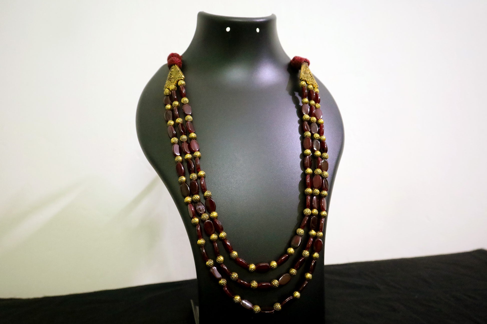 Closer view of 3 layered golden balls & oval glass beaded necklace on black mannequin - women fashion jewellery.