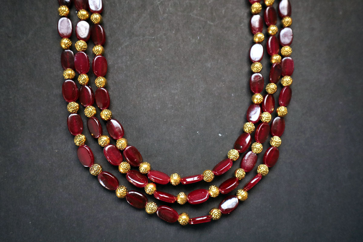 Bottom close-up of 3 layered golden balls & oval glass beaded necklace on a dark background – artificial jewellery for women