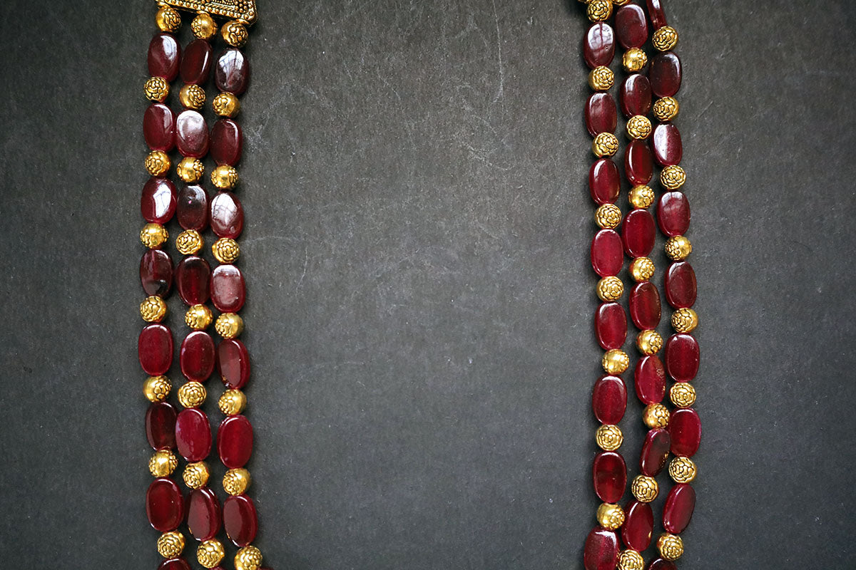 Close-up of layers of 3 layered golden balls & oval glass beaded necklace on a dark background – fashion jewellery online