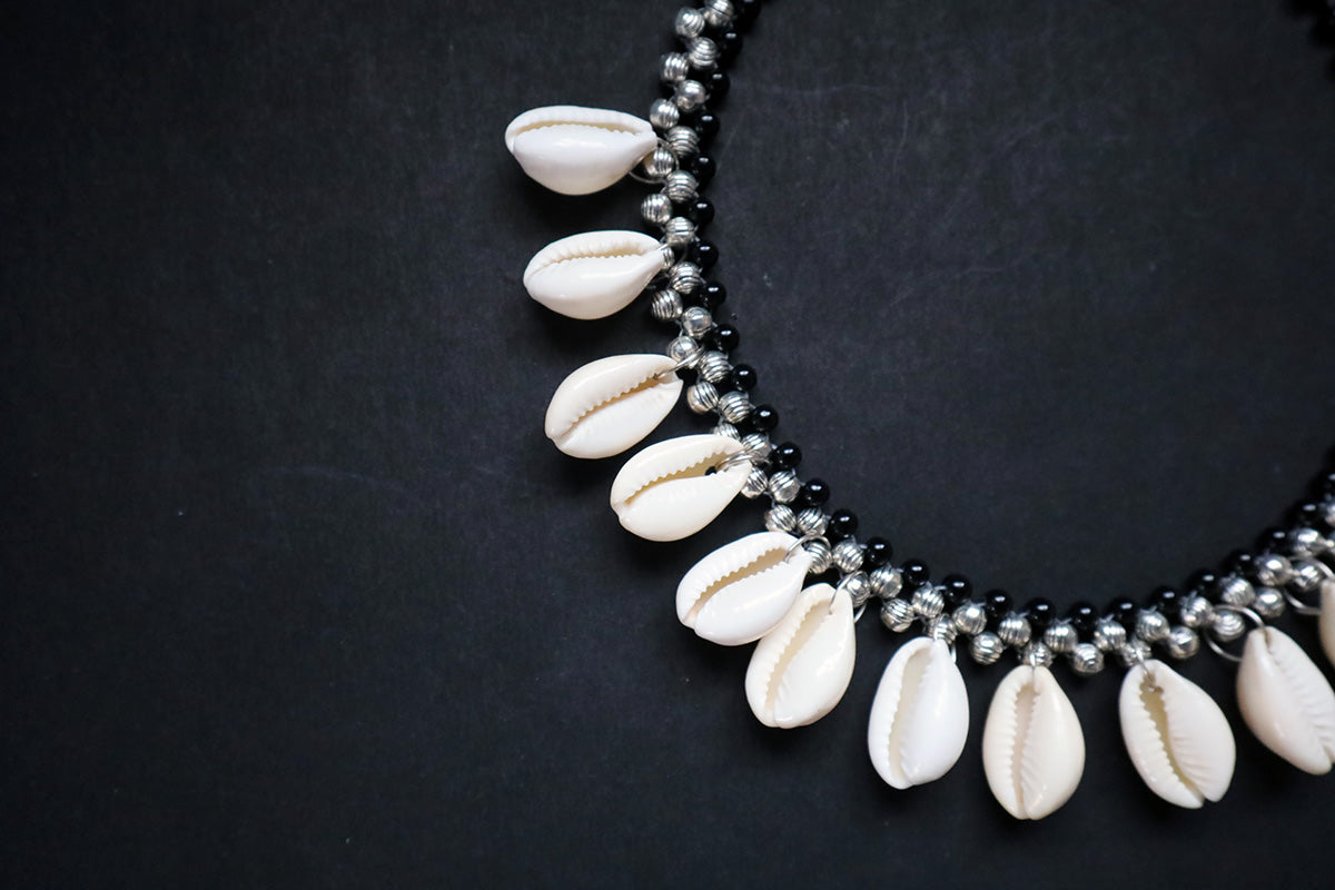 Close-up of left side of metal beads and cowrie silver colored necklace – fashion jewellery for women