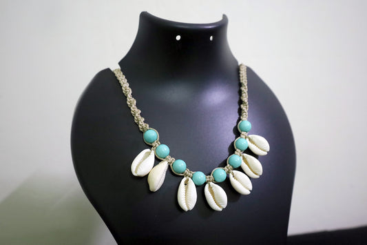 Necklace with turquoise beads and white shell-like pendants on a black mannequin.