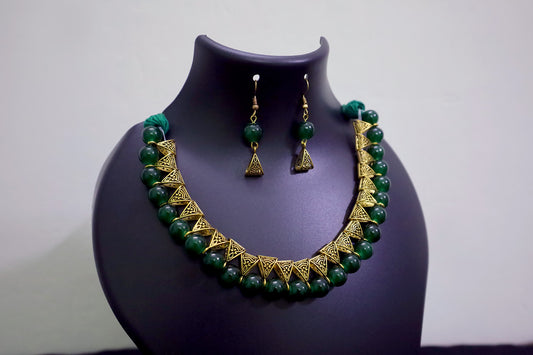 Closer view of green glass beads golden loop necklace set on black mannequin