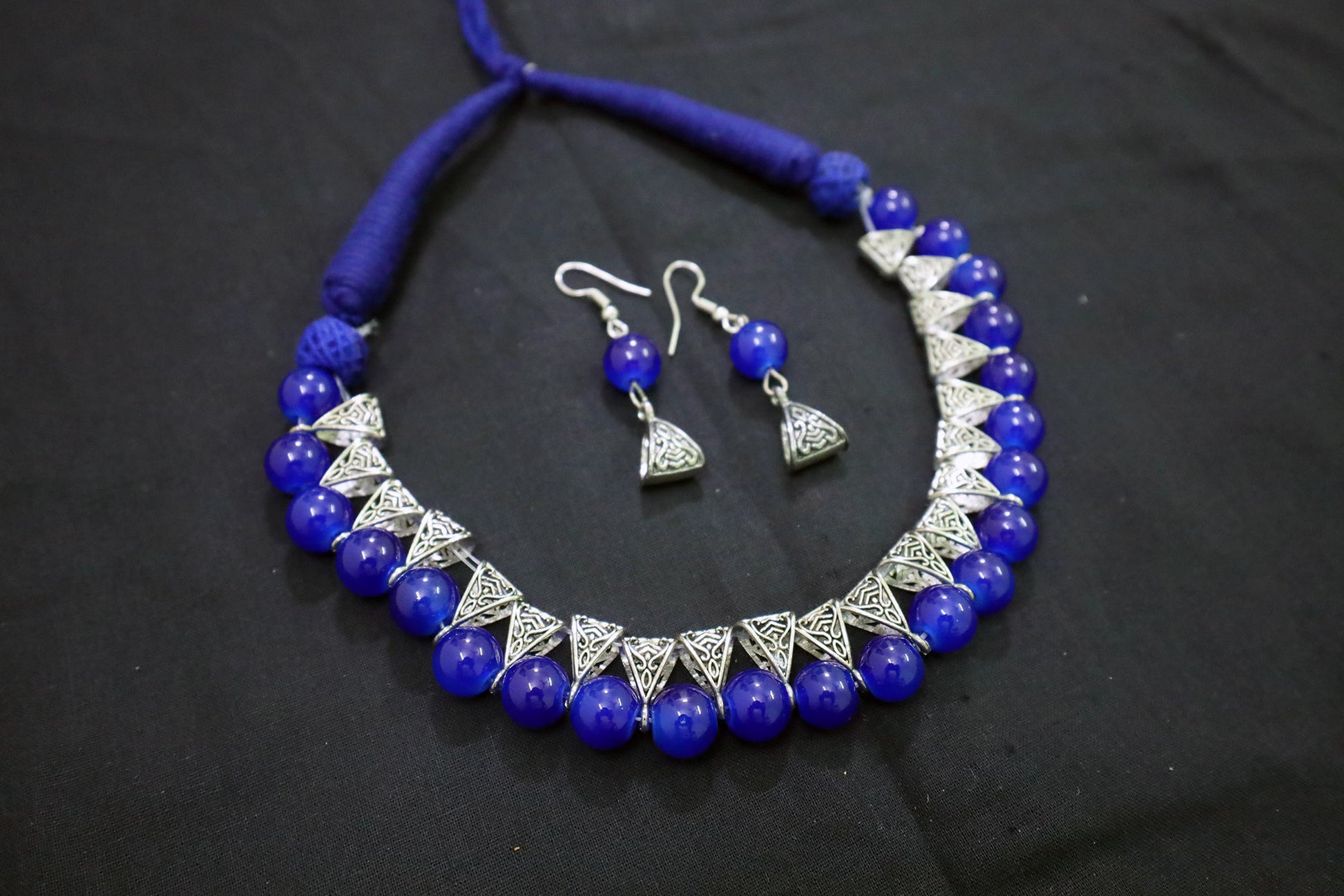 Angle view of navy blue glass beads silver loop necklace with earrings