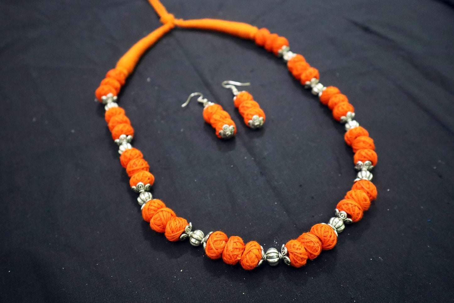 Angle view of orange oxidized balls and cotton balls necklace with earrings