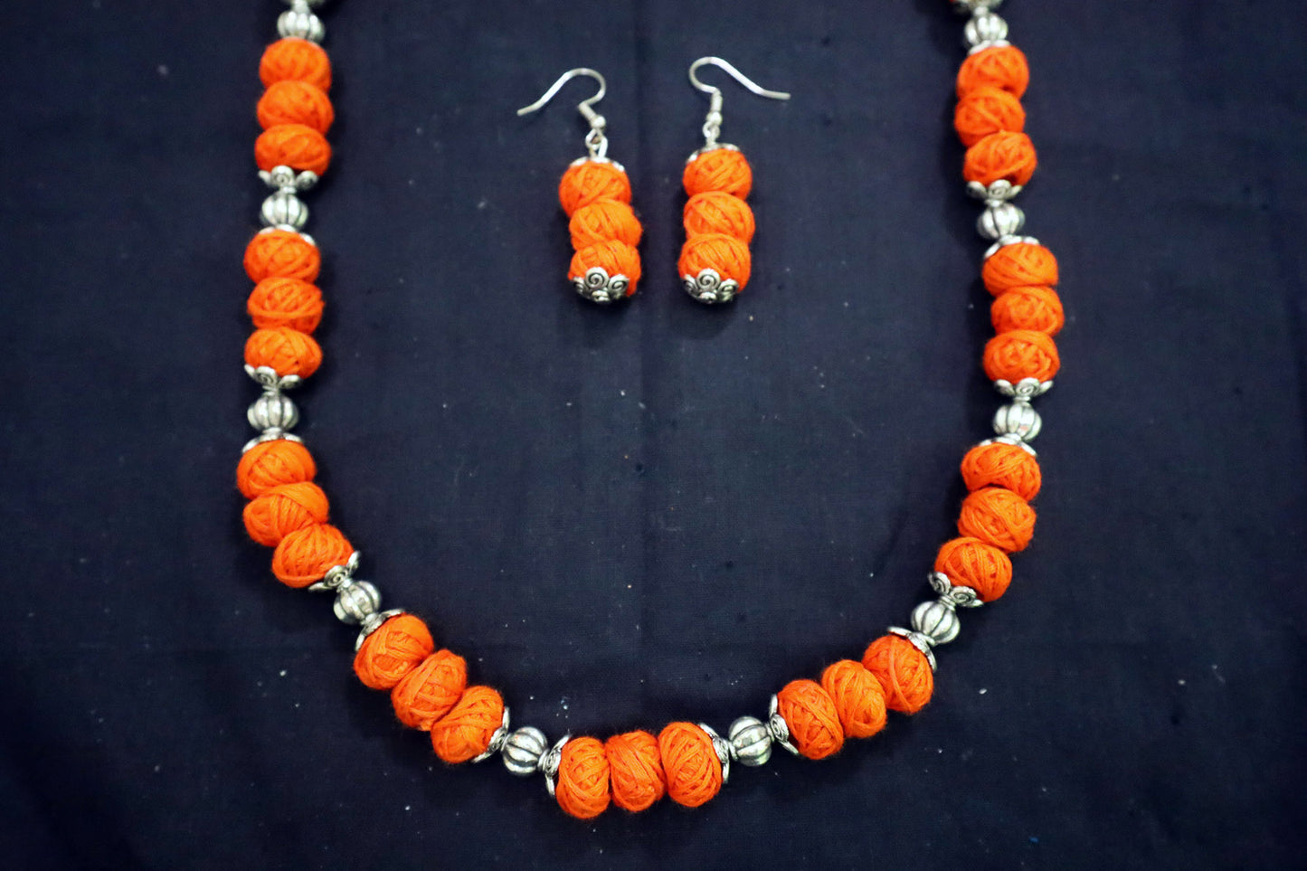 Bottom close-up of orange oxidized cotton balls long necklace and earrings