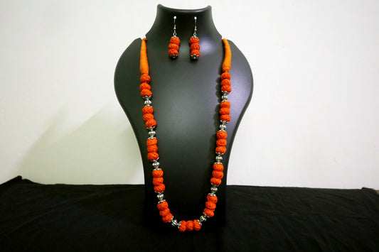 Closer view of orange oxidized balls and cotton balls long necklace with earrings on black mannequin