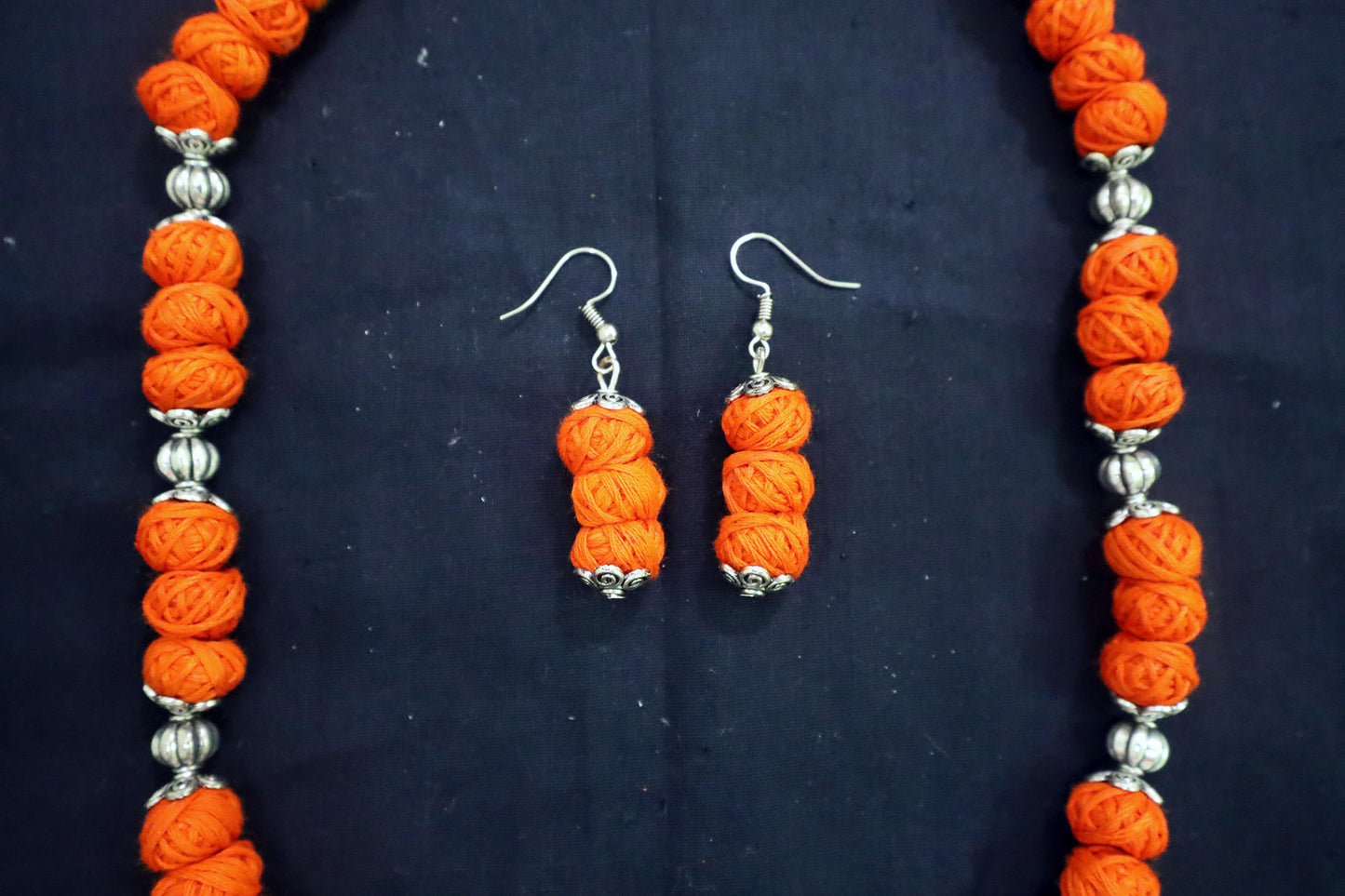 Middle section close-up of orange oxidized and cotton balls detailing on necklace
