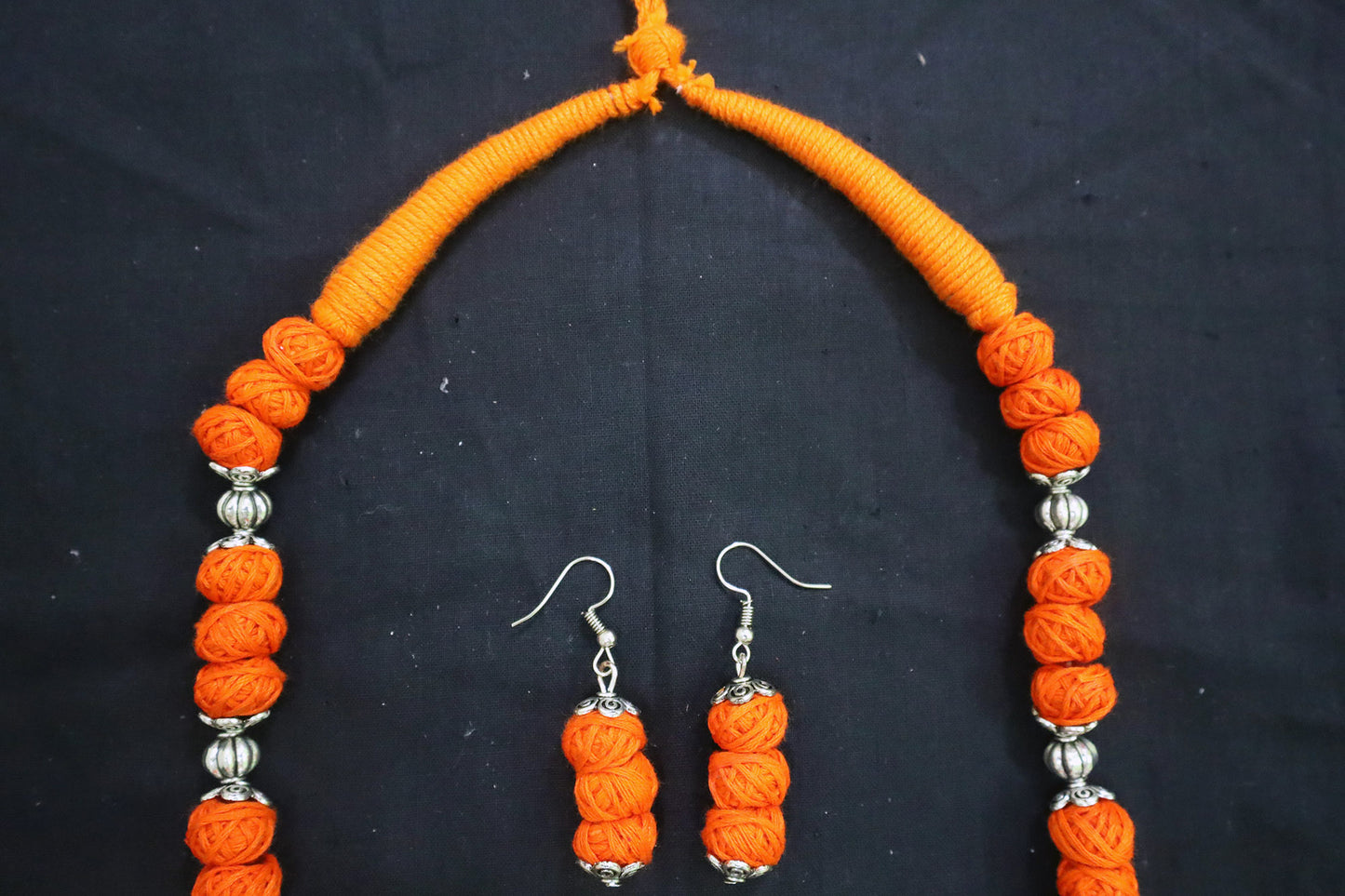 Top tassel close-up of orange oxidized cotton balls long necklace and earrings