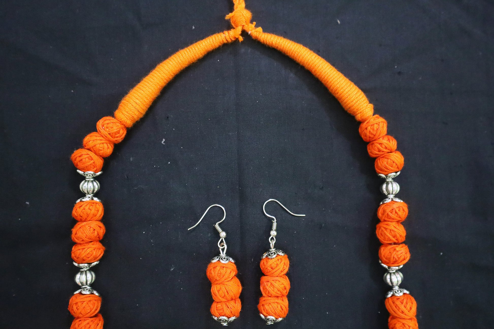 Top tassel close-up of orange oxidized cotton balls long necklace and earrings
