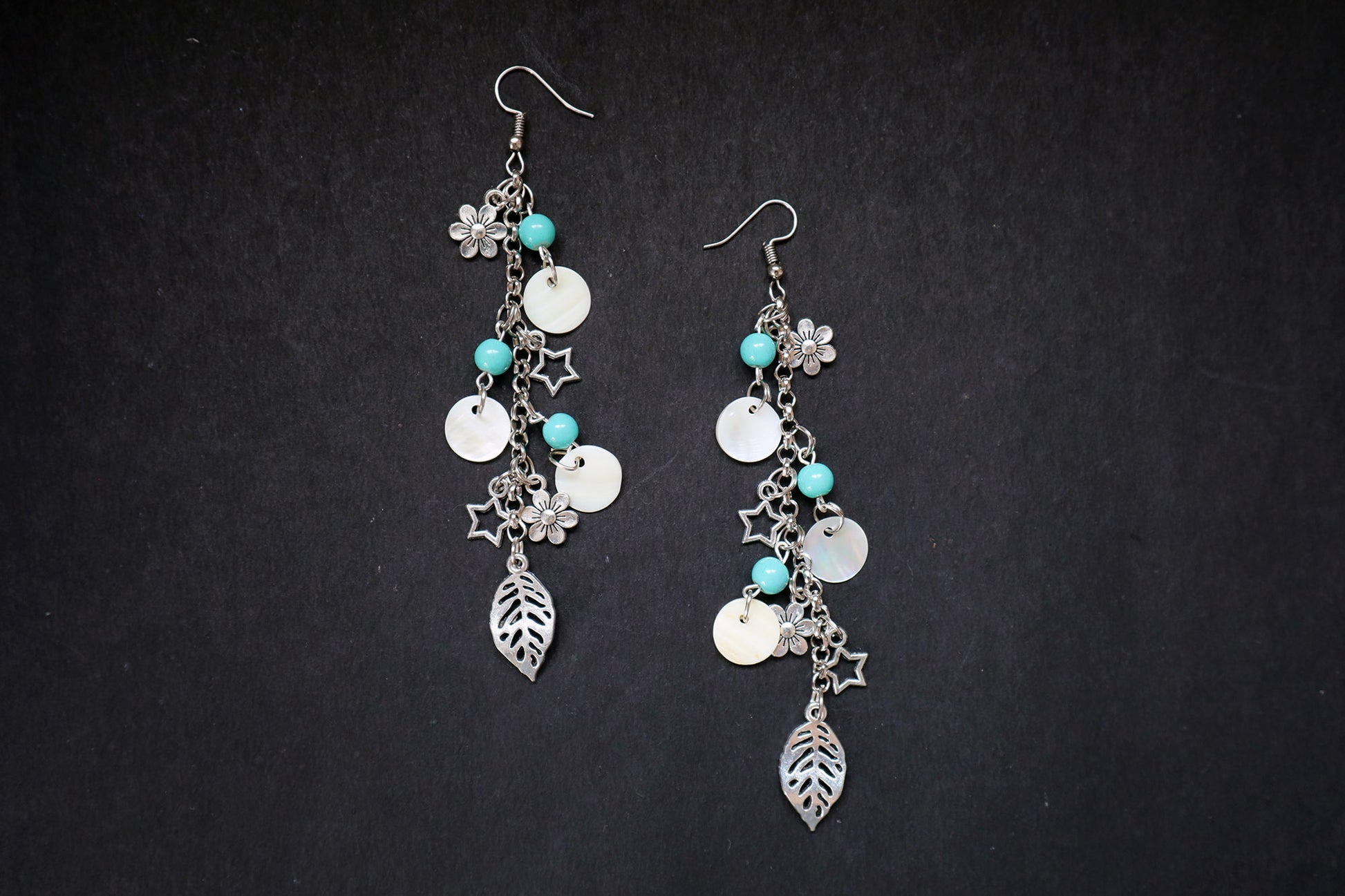 Top view of pearl and oxidized long chain earrings with big leaf, flower, and star charms