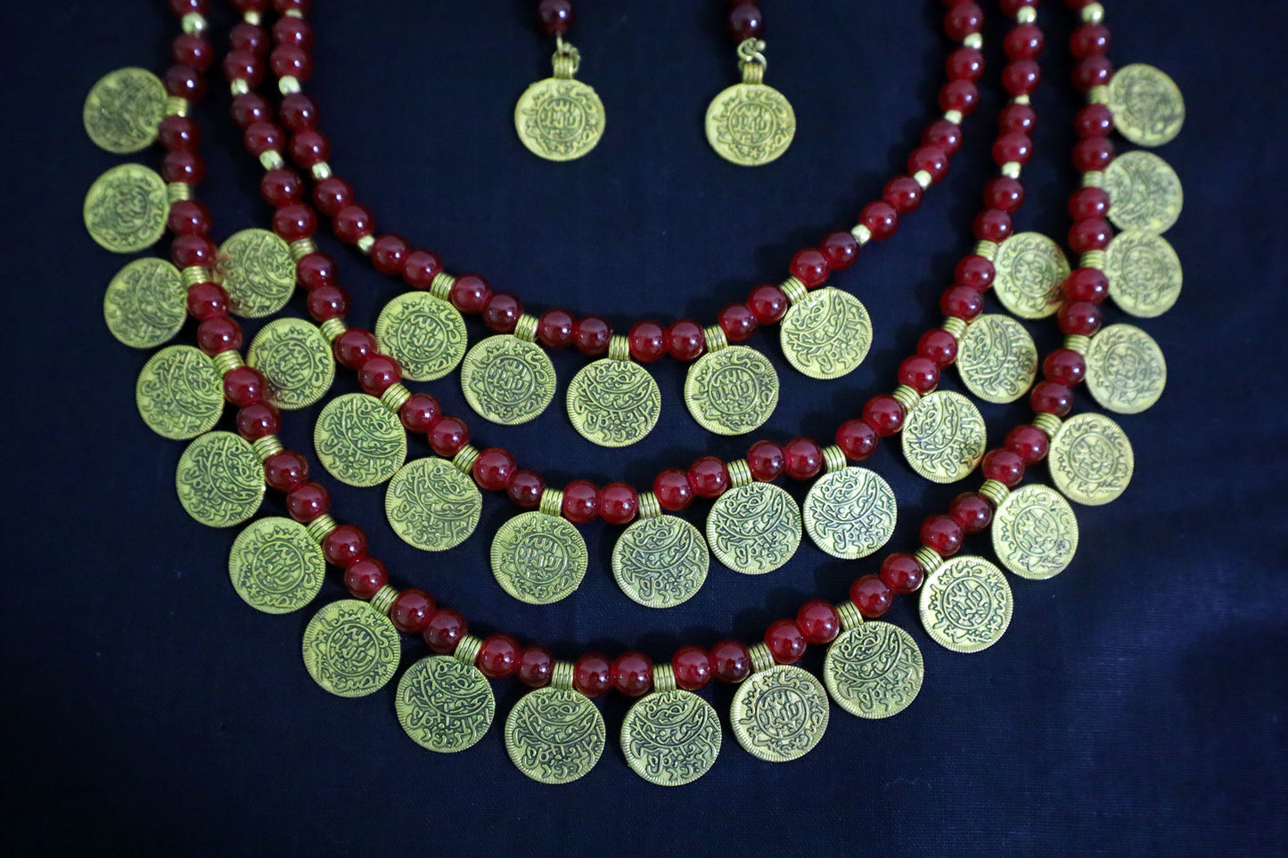 Bottom close-up of 3 layered glass beads and golden ginni necklace with earrings