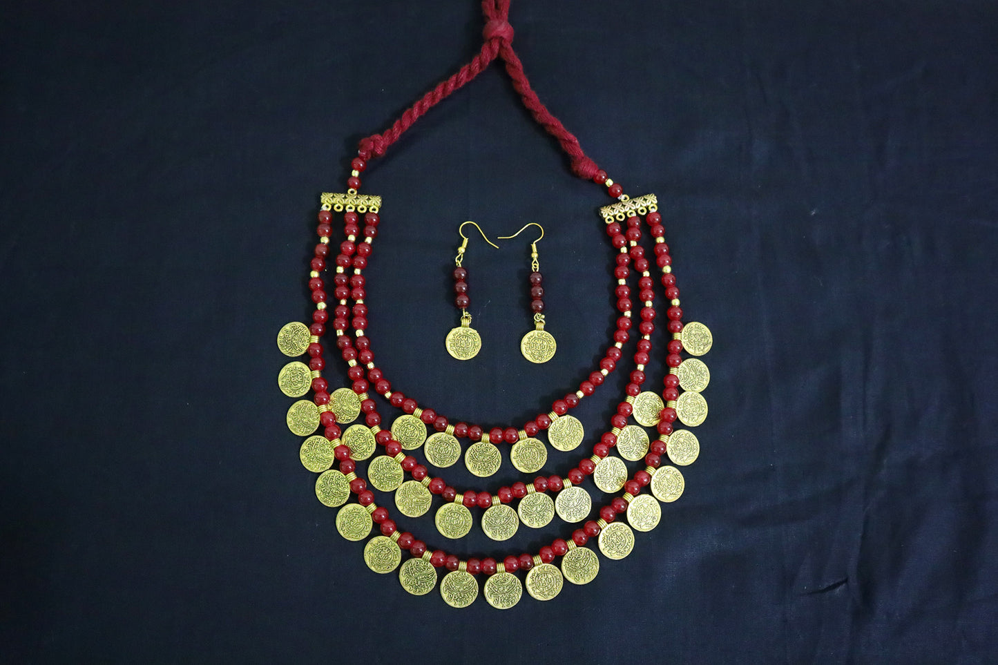 Top view of 3 layered glass beads and golden ginni necklace set with earrings on black background