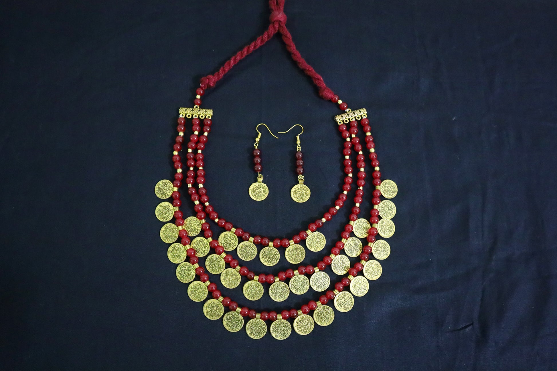 Top view of 3 layered glass beads and golden ginni necklace set with earrings on black background